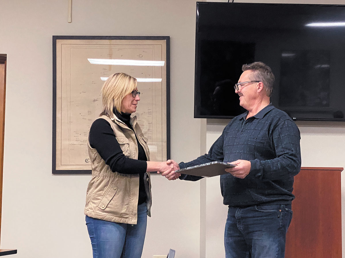 Village of Garrettsville fiscal officer shakes mayor Rick Patrick's hand after being acknowledged for her service to the village. 