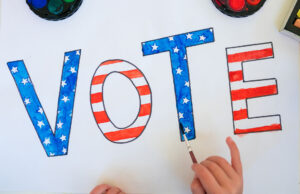 JAG Schools to Host League of Women Voters’ “Meet the Candidates Night” for the Garrettsville Area Child painting a "Vote" sign
