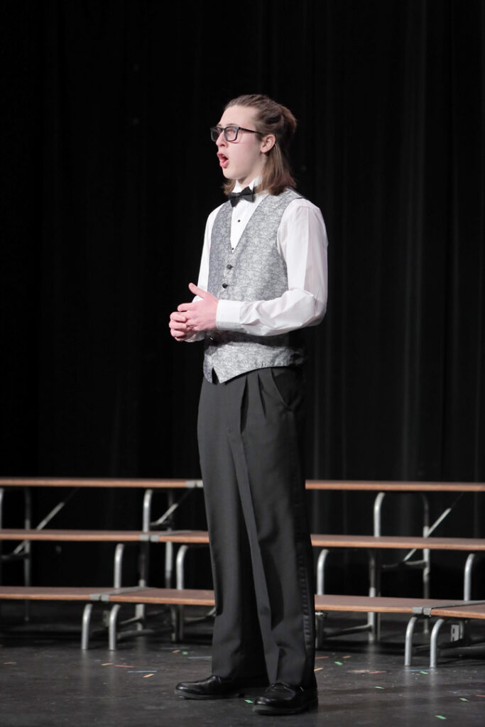 The James A. Garfield High School Concert Choir took center stage on January 28, 2025, for their Solo & Ensemble Concert at the Iva Walker Auditorium. Under the direction of Mr. Joel Logan, with support from Ms. Tori Mateos, student teacher from Kent State University, and Mr. John Eley, collaborative pianist, the evening showcased a blend of full-choir performances, soloists, and small ensembles, celebrating the hard work of students who had recently participated in the Ohio Music Education Association (OMEA) Solo & Ensemble contest. “This is the first time we’ve done one of these,” Logan remarked in his introduction. “I am trying to do a few new things to get the choir performing a little bit more for the community.” The concert opened with Natsu No Yo Wa (In the Summer Night), accompanied by Madelyn Smerkar on flute. Before the performance, Logan shared the poetic meaning behind the Japanese text: “The evening still seems present, but the dawn is here. To what region of the clouds has the wandering moon come home?” Though the winter weather outside was far from summery, Logan noted, “I thought the sentiment of the moon and that wandering about the dawn—it was a fitting, fitting piece for the winter here as well.” As the evening continued, standout solo performances included Lillian Adair singing The Fields Are Full by Armstrong Gibbs, a piece she had taken to contest just days before. “I think the judge got Lily’s score wrong,” Logan joked. “But that’s maybe just because I’m a little biased. I’m very proud of her singing.” Baritone Marshall Dahlen, a four-year choir member and senior, performed The Vagabond by Ralph Vaughan Williams. “A truly different piece than the other pieces you’re going to hear tonight,” Logan noted. Though Dahlen opted for a festival-style performance rather than a rating, Logan affirmed his skill: “You will hear here that he is well off to a great senior year in choir. “ thanking Dahlen for being in choir all four years of high school. A special feature of the concert was the Super Singerz, a self-named ensemble performing Homeward Bound, a Class C contest piece. “They received a 1, a superior rating, at Solo & Ensemble,” Logan proudly announced. He also extended a special thanks to Ollie May for joining the group, despite not being in choir every day: “We forgive him for that—still glad that he is singing.” The night concluded with For Good from the musical Wicked, arranged by Huff. Before the performance, Logan shared an amusing anecdote: “If you’ve seen the movie Wicked or you have seen the show—it has been out a couple of years now—this is principal Kathleen Kisabeth’s favorite from it. No pressure, everybody. No pressure.” He also emphasized the value of singing as a lifelong pursuit: “A community that sings together… stays together! Even principals can come and sing, and even student teachers who tell their band students she’s not a singer can sing.” The High School Concert Choir featured a talented lineup across all voice sections: Sopranos: Lillian Adair, Diamond Dyson, Sierra Foy, Abygail Seiler*, Zoey Zimmerman Altos: Samantha Barker, Hallie Cebulla*, Remy Ewell, Madison Hayhurst, Alexis Phillips, Olivia Seaborn Tenor/Bass: Maximus Brewster, Jaxen Cushing, Marshall Dahlen*#, Wyatt Manista, Quinn Roborecki (*Senior, # Four-Year Choir Member, + Super Singerz)