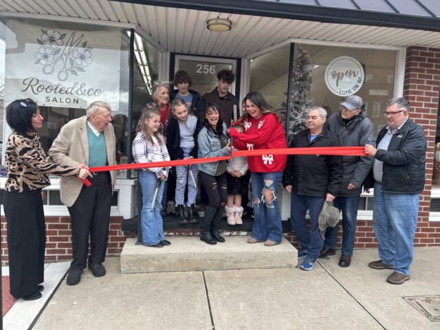 Sara Davis (right center) and Morgan Taylor (left center) proudly cut the ribbon to commemorate the grand opening of Rooted & Co Salon/Photo by Daniel Sherriff