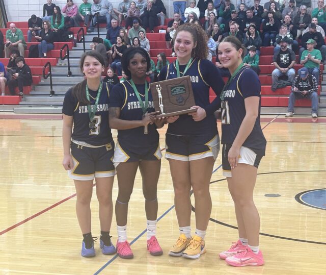 The Streetsboro girls' basketball team holds the OHSAA Division IV Northeast 2 district runner-up trophy following a 50-40 loss against West Branch in the district championship last Saturday at Lordstown High School/Photo by Daniel Sherriff